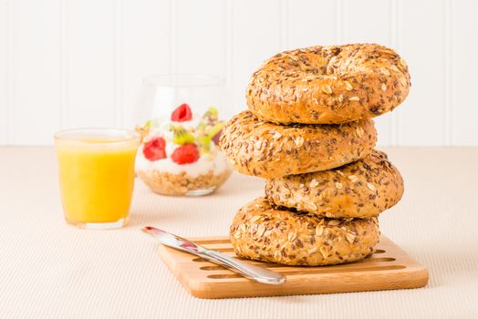 Stack of muesli bagels with orange juice and a fruit parfait.