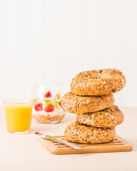 Stack of muesli bagels served for breakfast with juice and fruit.