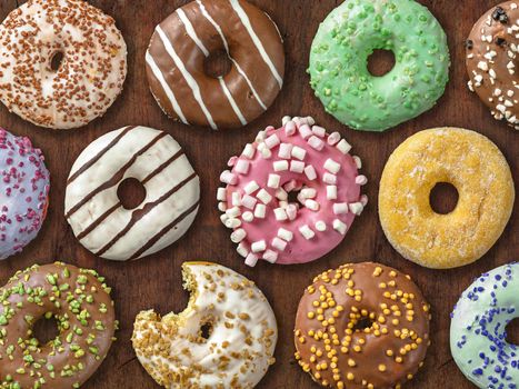 Photo of twelve different donuts over wood background.