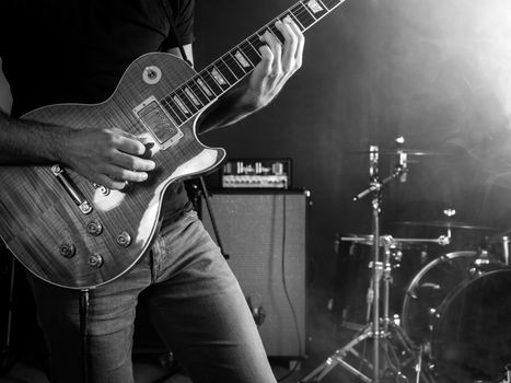 Photo of a guitar player playing on stage done in black and white.