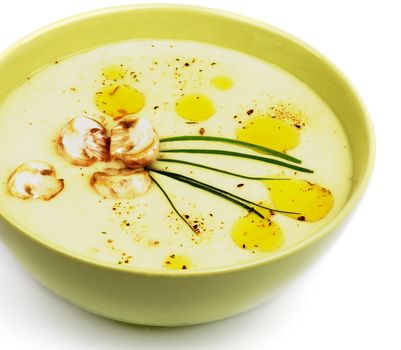 Delicious Mushroom Creamy Soup with Champignon Decorated with Olive Oil and Greens in Yellow Bowl closeup on white background