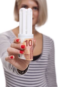 Woman holding an eco-friendly light bulb with a 10 Euro banknote threaded through it in a conceptual image of efficiency and savings