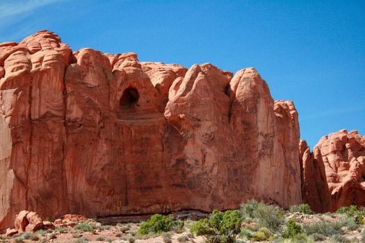 A red rock formation with a cave carved out of Entrada Sandstone in Arches National Park near Moab Utah.