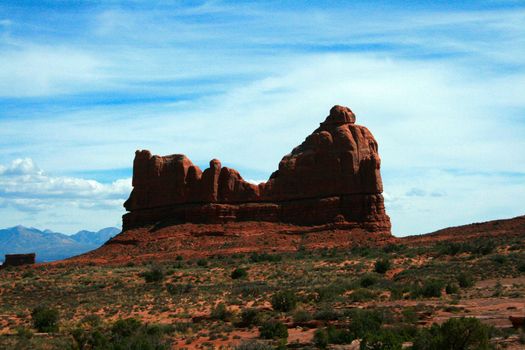 Courthouse Rock towers over the desert sands and scrubland at Arches National Park near Moab Utah, USA.