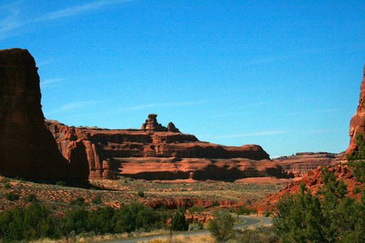 A Utah highway leads visitors to marvelous wonders of red stone in Arches National Park, USA.