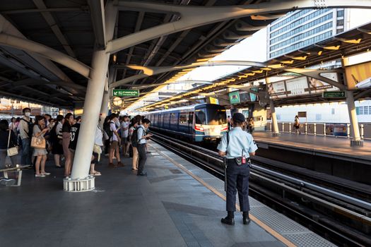 Bangkok, Thailand - January 18, 2016 : Security guard watching people while they waiting for the train to come to ensure safety of the passengers at BTS National Stadium station in the rush hour. Daily passengers of BTS skytrain is around 700,000