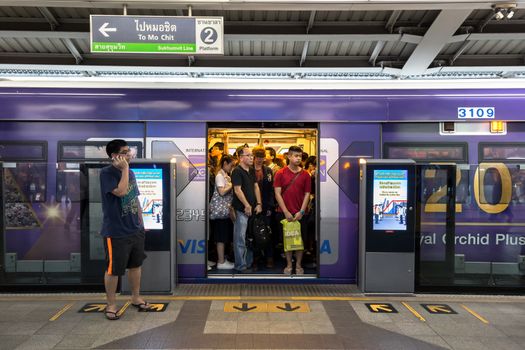 Bangkok, Thailand - January 18, 2016 : BTS skytrain full of people in the train and one person waiting while calling on the phone in the waiting zone with sign of the train destination on above at BTS Siam staion in the evening. Daily passengers of BTS skytrain is around 700,000