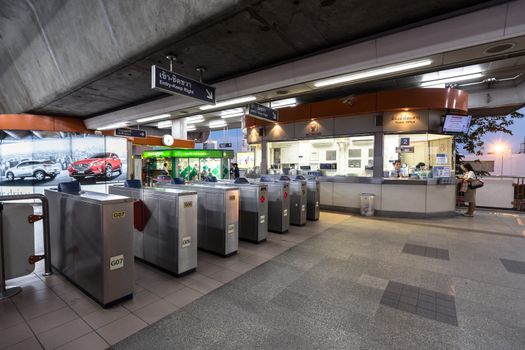 Bangkok, Thailand - January 18, 2016 : Ticket barriers machine of the BTS skytrain with nobody using it and the officers in the ticket office and unidentified passenger buying a ticket at the evening. Daily passengers of BTS skytrain is around 700,000