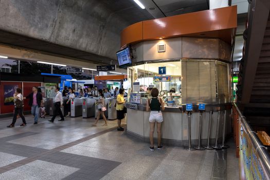 Bangkok, Thailand - January 18, 2016 : Ticket office at the BTS Mo Chit station at the evening with 2 people buying a ticket and a lot of people walking out from the inside of the station. Daily passengers of BTS skytrain is around 700,000.