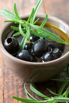 Black olives in clay bowl and rosemary set