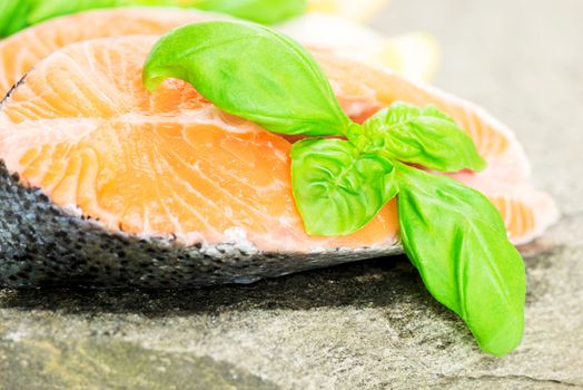 Salmon cuts on stone with basil and lemon close up