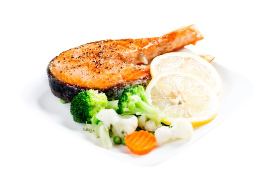 Grilled salmon with steamed vegetables on plate isolated on white background