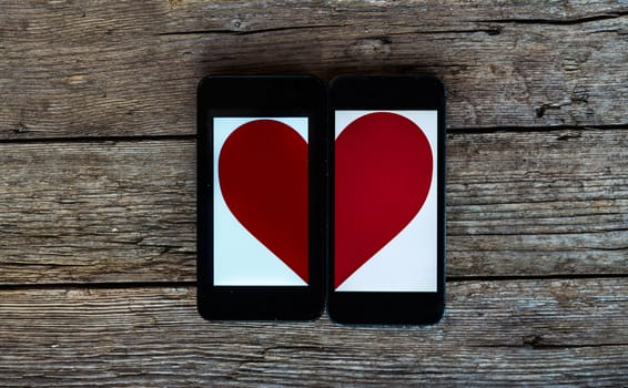 Two Cellphone With Half Heart Symbol on wooden background