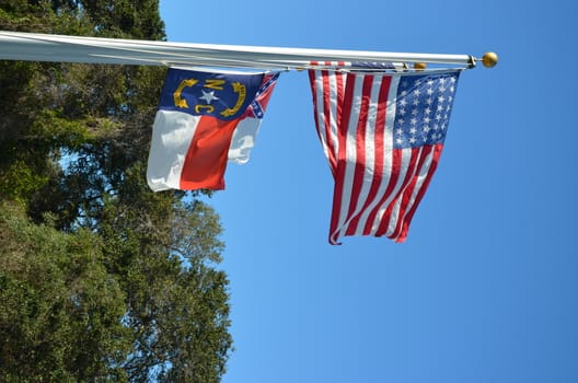 American flag flying in the wind and a North Carolina Flag next to it.