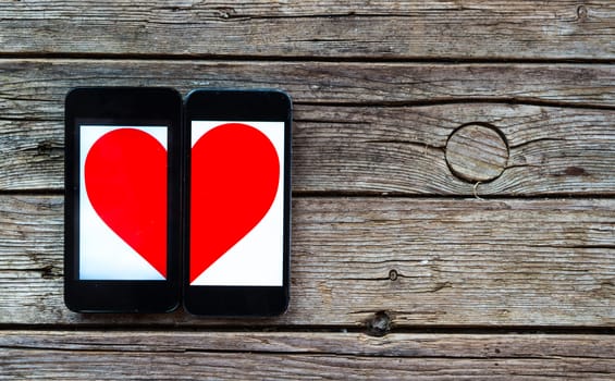 Two Cellphones With Half Heart Symbol on wooden background
