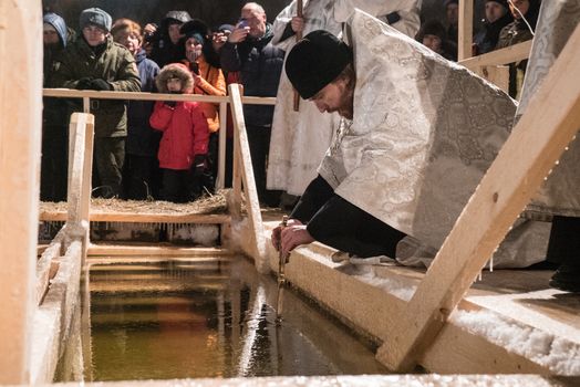 RUSSIA, Moscow: A priest blesses the water on January 19, 2016 in Moscow, as part of Epiphany ceremonies.Among Orthodox Christians, the feast of Epiphany celebrates the day the spirit of God descended upon believers in the shape of a dove during Jesus Christ's baptism in the river Jordan. At midnight, worshippers walked in procession from one of Moscow's Orthodox temples to the lake. Tents for warming and changing clothes were arranged by military people and the Ministry of Emergency (EMERCOM). Women and little children entered the water at the temperature 10 degrees below zero. Some people stayed in water just a few seconds, others, praying, plunged several times. 