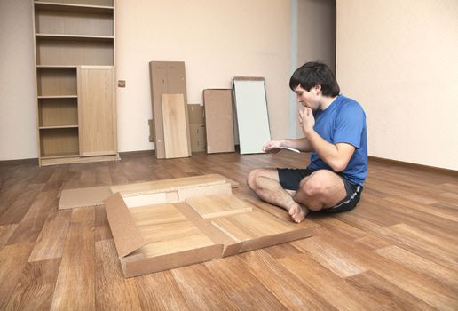 Young man puzzled about assembling flatpack closet