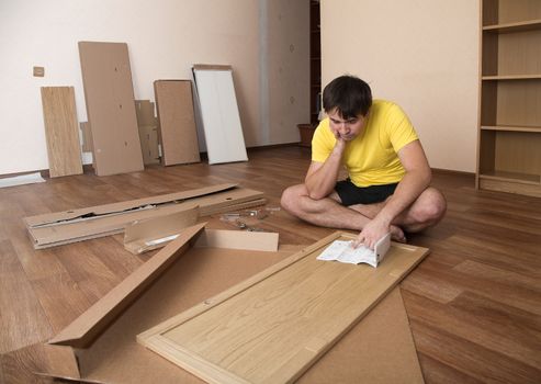 Young man puzzled about assembling flatpack closet