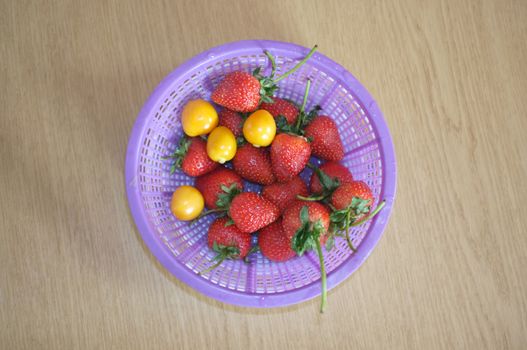 Fresh strawberry and cape gooseberry in plastic basket
