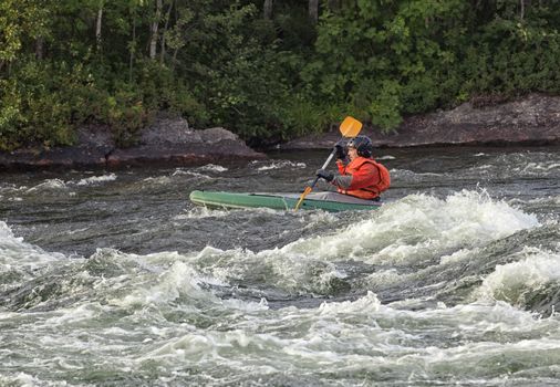 Kayaker in the  whitewater of a river Umba in Russia