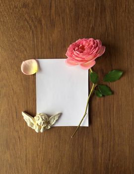 Vintage rose and blank photo frame Cupids on old wooden background