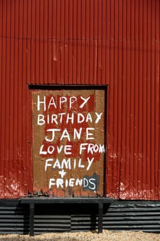 Handpainted birthday wishes written on an a door of a red abandoned building.