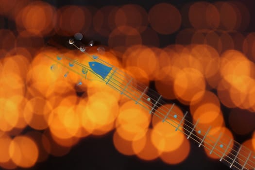 A background of blur orange lights and a guitar fretboard and keys.