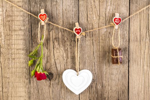 Red rose with white shape heart and chocolate on wooden background