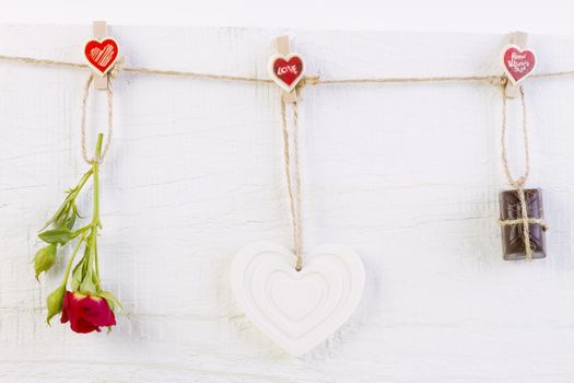 Red rose with white shape heart and chocolate on white wooden background