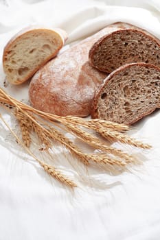 Bakery concept. Freshness bread set on white tablecloth near wheat ears