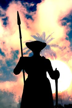 A silhouette of an ancient Indian warrior guard with a spear, on the backdrop the dusky sky.
