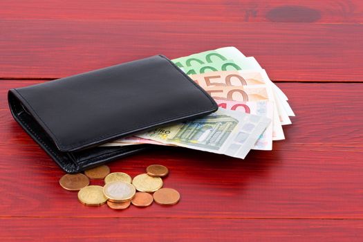 Wallet with European money on a wooden background