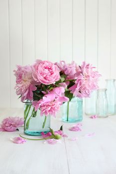 Pink peonies in glass jars on table