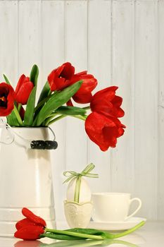 Red tulips and egg with bow on table