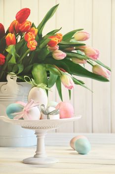 Colored eggs with bows with tulips in background