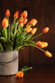 Yellow and orange tulips in old bucket on table