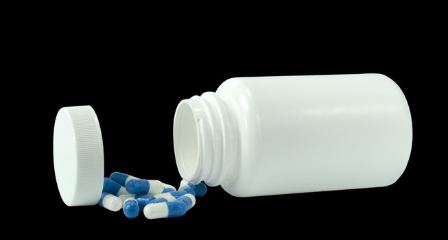 some pills of a white and blue colors with white jar on a black background
