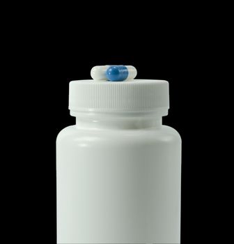 two pills of a white and blue colors with white jar on a black background