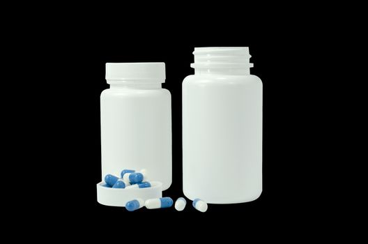 some pills of a white and blue colors with two white jar on a black background