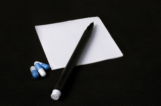 prescription, pills and pen on a black background