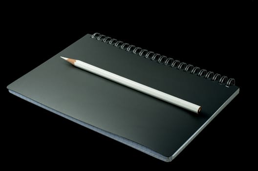 open notebook with pencil on a black background