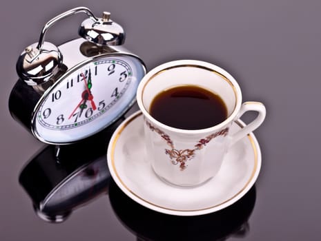 cup of coffee and watch the table on a dark background