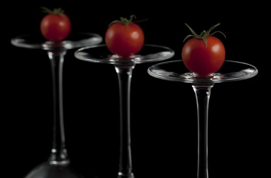 Red cherry tomatoes on the overturned glasses.