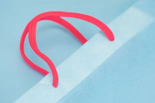 Close up pink rope carry with light blue paper bag.