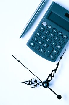 Time is money. Calculator and pen near clock face