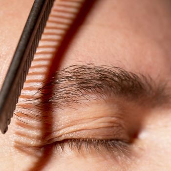 Portrait of man removing eyebrow hairs with scissors