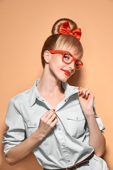 Beauty fashion woman in stylish glasses smiling. Attractive pretty happy blonde hipster girl, emotional. Confidence, success, Pinup hairstyle red bow. Unusual playful, expression. Vintage, vanilla