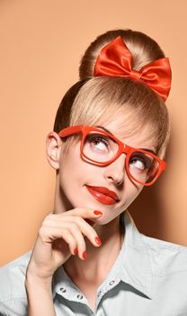 Beauty fashion woman in stylish glasses thinking, idea. Attractive pretty blonde hipster girl smiling. Confidence, success, Pinup hairstyle,red bow makeup. Unusual playful, expression.Vintage, vanilla