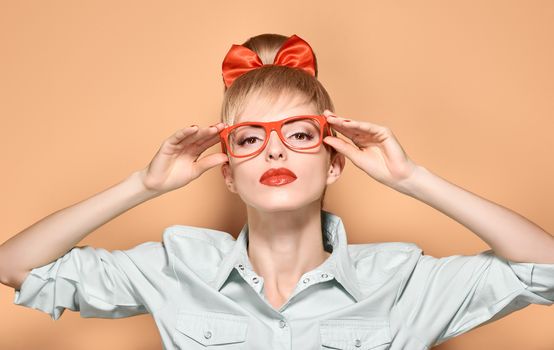 Beauty fashion portrait woman in stylish glasses. Attractive pretty blonde sexy hipster girl. Confidence, success, Pinup hairstyle, trendy red bow makeu,lips.Unusual playful, creative.Vintage, vanilla
