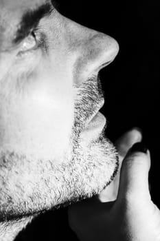 Close-up of mature man resting chin on palm, low key, black and white